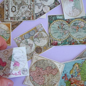 May include: A collection of vintage-style map prints, featuring detailed illustrations of continents and oceans. The maps are in various sizes and shapes, with a color palette of muted greens, blues, and browns. Some maps have decorative borders and text.