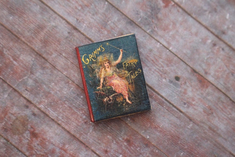 May include: A vintage book titled "Grimm's Fairy Tales" with a blue cover and a colorful illustration of a fairy on the front.