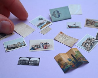 May include: A collection of miniature vintage ephemera, including postcards, letters, and a small booklet, with detailed illustrations and aged paper textures. The items are arranged on a light purple surface.