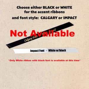 May include: Image shows two ribbons, one black and one white, with text indicating font styles and availability. The black ribbon has "Calgary Font" and "gold" text. The white ribbon says "Impact Font - White w/black". Text states "Not Available".