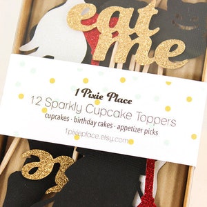May include: A set of 12 sparkly cupcake toppers featuring a white rabbit, a red heart, a black cat, and the words "eat me" in gold glitter. The toppers are packaged in a clear plastic box with a white label that reads "1 Pixie Place 12 Sparkly Cupcake Toppers cupcakes birthday cakes appetizer picks 1pixieplace.etsy.com".