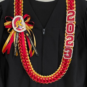 May include: A red and gold graduation lei with the year "2023" in glittery letters. The lei features a ribbon with the text "La Canada High School 2023" and a ribbon that says "Congratulations Graduate!"