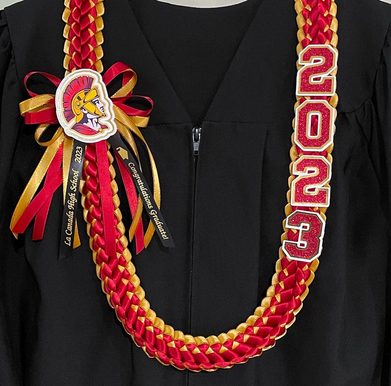 May include: A red and gold graduation lei with the year "2023" in glittery letters. The lei features a ribbon with the text "La Canada High School 2023" and a ribbon that says "Congratulations Graduate!"