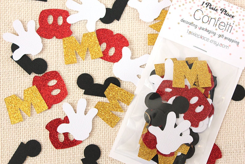 May include: A bag of confetti featuring Mickey Mouse themed shapes in red, gold, black, and white. The confetti includes Mickey Mouse ears, hands, and the letter "M". The bag has a label that reads "1 Pixie Place Confetti decorating - packaging - gift wrapping 1pixieplace.etsy.com"