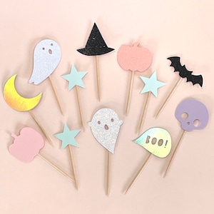 May include: A set of 12 Halloween-themed cake toppers. The toppers are made of glitter cardstock and feature various designs, including ghosts, pumpkins, bats, stars, and a witch's hat. The toppers are perfect for adding a festive touch to your Halloween party.