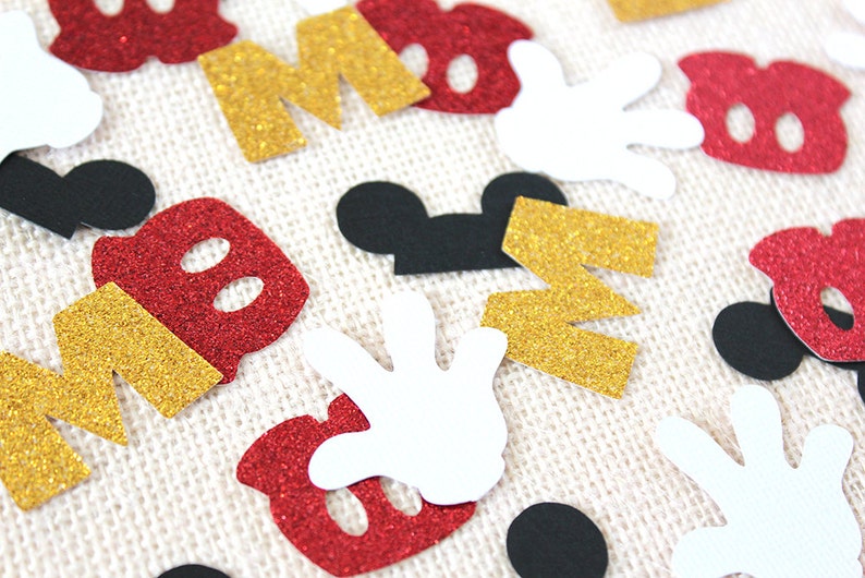 May include: Assortment of red, gold, black and white confetti featuring Mickey Mouse ears, gloves, and the letters "M" and "O".