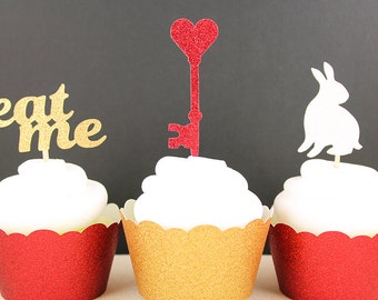May include: Three cupcakes with different toppers. The cupcake on the left has a gold glitter "eat me" topper. The cupcake in the middle has a red glitter key with a heart at the top. The cupcake on the right has a white glitter rabbit topper. The cupcakes are decorated with red, gold, and white glitter cupcake liners.