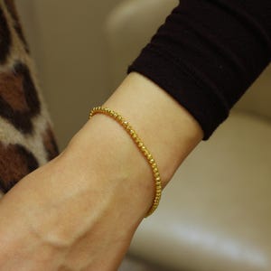 Puede incluir: Un brazalete de cuentas doradas en la mu&ntilde;eca.