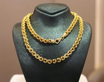 May include: A gold chain necklace on a black display stand. The chain is made of thick, linked, oval-shaped pieces.