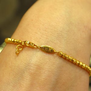 Puede incluir: Un brazalete de oro con un dise&ntilde;o de cuerda trenzada y un cierre con la inscripci&oacute;n "22 916 991".