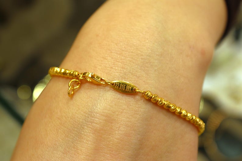 Puede incluir: Un brazalete de oro con un dise&ntilde;o de cuerda trenzada y un cierre con la inscripci&oacute;n "22 916 991".