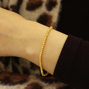 Puede incluir: Un brazalete de oro con un dise&ntilde;o texturizado y de cuentas.