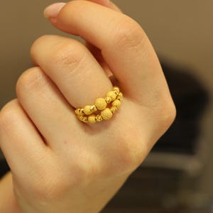 May include: A gold ring with a double row of textured round beads.