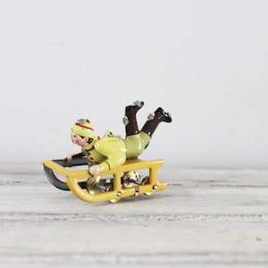 Adorno de árbol vintage de trineo amarillo con niño con ropa de invierno, trineo amarillo estilo juguete antiguo, miniatura coleccionable vintage, adorno de árbol
