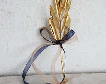 May include: A gold olive branch with a navy blue and beige ribbon tied around the stem.