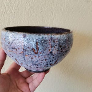 May include: A small, round ceramic bowl with a speckled glaze in shades of blue, brown, and white.
