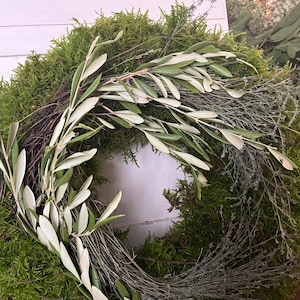 May include: A green moss wreath with olive branches and sprigs of dried greenery.