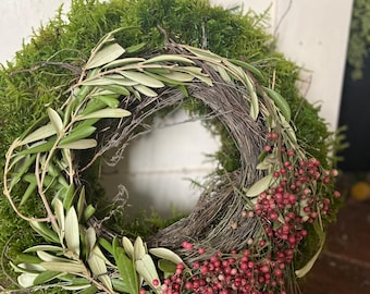 May include: A green moss wreath with olive branches and pink berries.