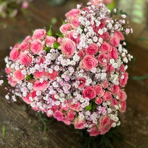 Peut inclure: Une composition florale en forme de cœur composée de roses roses et de gypsophile blanche.