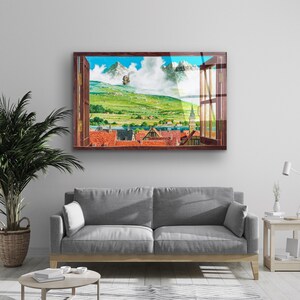 May include: A framed print of a window view with a green landscape, a small town, and a flying ship in the distance. The window frame is brown wood.
