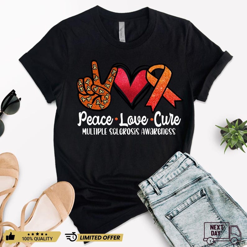 Puede incluir: Camiseta negra con un signo de paz hecho de cintas naranjas y un coraz&oacute;n rojo con una cinta naranja. El texto "Peace Love Cure" y "Multiple Sclerosis Awareness" est&aacute; impreso en la camiseta.