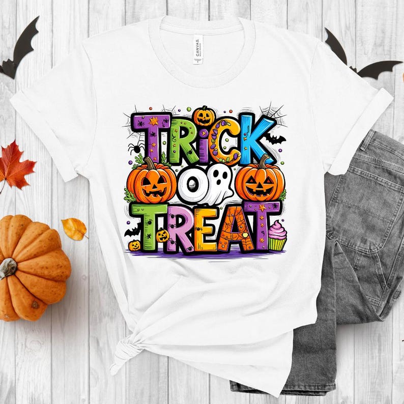 May include: White t-shirt with a colorful graphic design that says "Trick or Treat". The design features pumpkins, ghosts, bats, and candy.