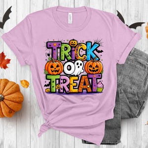 May include: A pink t-shirt with a colorful graphic that says "Trick or Treat" with pumpkins, a ghost, and a cupcake.