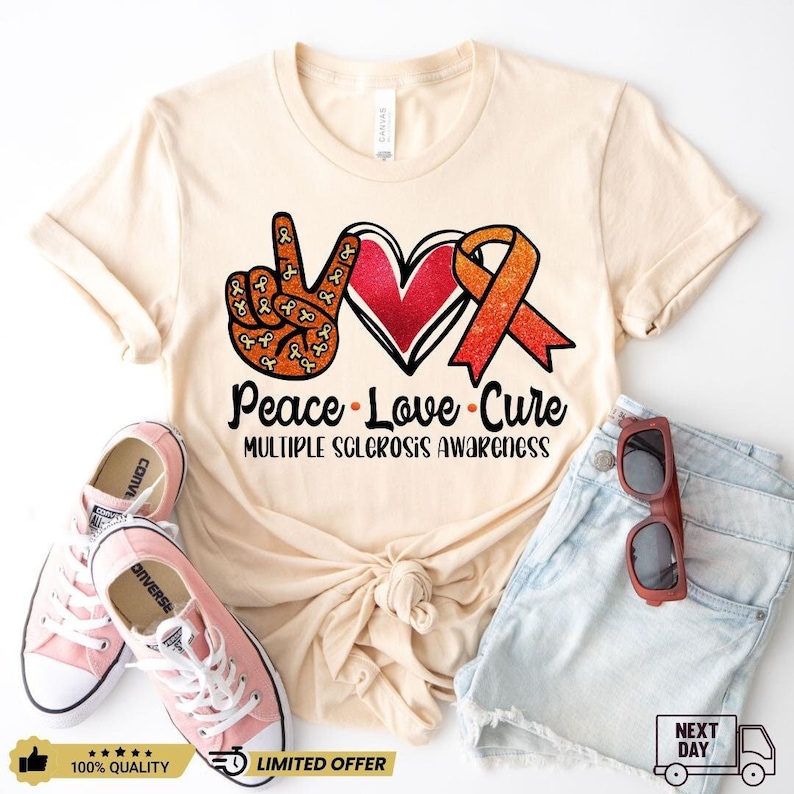 Puede incluir: Una camiseta beige con un signo de paz, un coraz&oacute;n y una cinta naranja con el texto "Peace Love Cure" y "Multiple Sclerosis Awareness".