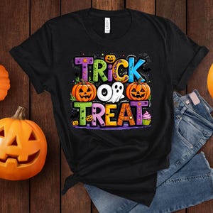 May include: Black t-shirt with a colorful "Trick or Treat" graphic featuring pumpkins, a ghost, and a cupcake.