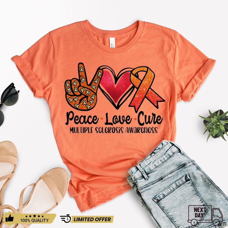 Puede incluir: Camiseta naranja con un dise&ntilde;o de signo de paz, coraz&oacute;n y cinta. El texto "Peace Love Cure" y "Multiple Sclerosis Awareness" est&aacute; impreso en la camiseta.