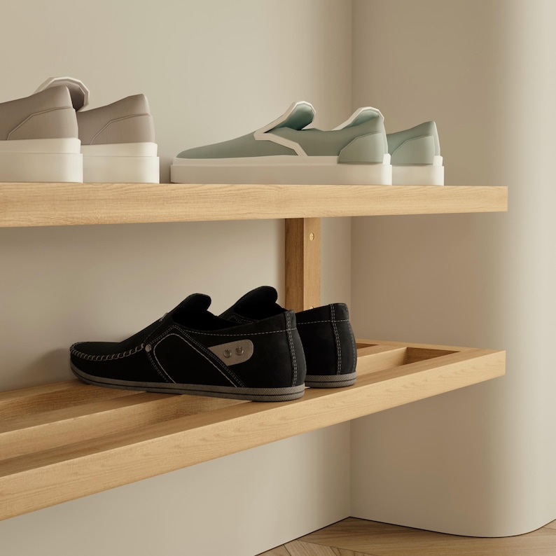 May include: A display of shoes on wooden shelves. The top shelf features two pairs of platform sneakers in neutral tones and a pair of light green slip-on sneakers. The bottom shelf displays a pair of black loafers.