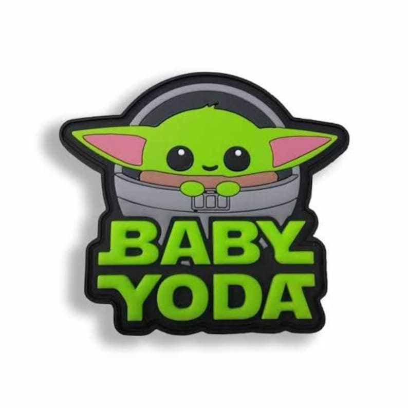 May include: A green Baby Yoda character in a gray carrier, with pink-lined ears and large black eyes. The words "BABY YODA" are in green block letters on a black background.