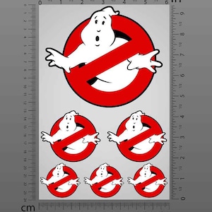 Può includere: Un foglio di adesivi riflettenti con il logo Ghostbusters. Il design include un fantasma bianco all'interno di un cerchio rosso con una linea diagonale rossa. Il foglio ha un righello in pollici e centimetri. Gli adesivi sono resistenti all'acqua, al carburante, all'olio e agli agenti chimici.