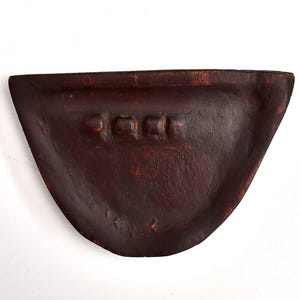 May include: A dark brown, semi-circular wooden bowl with a carved design of three square shapes near the top edge. The bowl has a smooth, curved interior and a rustic, handcrafted appearance.