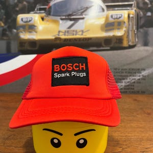 May include: Red and black trucker hat with a black patch that says "BOSCH Spark Plugs".