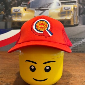 May include: Red mesh trucker hat with a white, blue, and red embroidered patch that says "The British Motor Corporation Ltd. BMC".