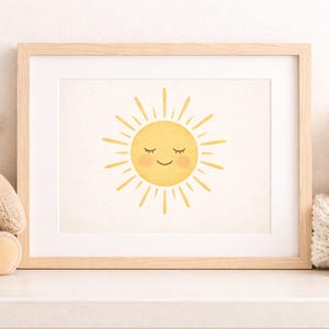 Peut inclure: Une impression encadrée à l'aquarelle représentant un soleil souriant aux yeux fermés et aux rayons jaunes. Un ours en peluche beige avec un nœud crème et une décoration en forme d'étoile et de lune blanche sont de chaque côté.