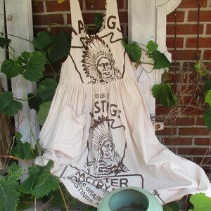 May include: A white cotton apron with a brown print of an American Indian chief and the text "Master By" and "100 LB. Bags Grain Postings".