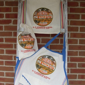 May include: A collection of vintage-style kitchen textiles, including an apron, a flour sack, and a dish towel. Each item features a circular logo with the text "French's White Lily Flour" in orange and brown, with blue and red stripes.