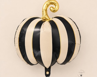 May include: A pumpkin-shaped foil balloon featuring alternating vertical stripes in black and cream colors. The balloon has a metallic gold stem at the top that curls to the right. A small logo with the text Designed by Moose is visible.
