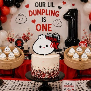 May include: A first birthday party display featuring a white cake with red and black sprinkles, topped with a dumpling cutout reading Our Little Dumpling Is One. Two bamboo steamers hold cupcakes with dumpling toppers, alongside a large black number one balloon and a backdrop with the text Our Lil Dumpling Is One.
