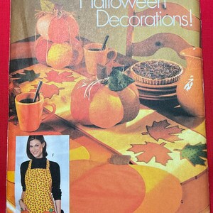May include: Butterick Halloween Decorations sewing pattern. The cover features a collage of fall-themed items, including pumpkin decorations, a pie, and an apron with pumpkin pockets. The text "Halloween Decorations!" is prominently displayed.
