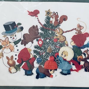 May include: An embroidered print featuring a snowman, children in winter clothing, and various woodland animals decorating a Christmas tree. The scene includes a squirrel, a mouse, a raccoon, and rabbits, all arranged around a central pine tree.