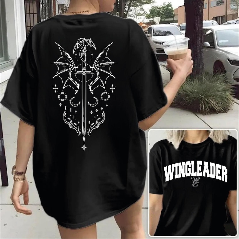 A person wearing a black t-shirt with a white graphic design on the back, including a dragon, sword, and stars.