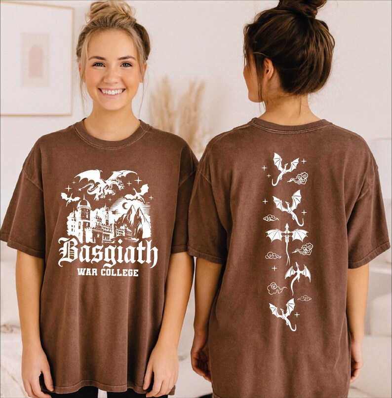 A woman wearing a brown t-shirt with a graphic design featuring a castle and dragons, smiling at the camera.