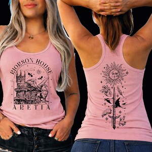 a woman wearing a pink tank top with a graphic design on the front and back.