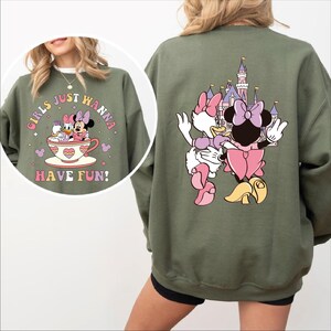 A green sweatshirt with a cartoon image of Minnie Mouse and Donald Duck on it, along with the text "Girls just wanna have fun!" printed on it.