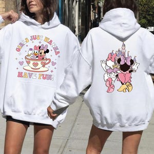 A woman wearing a white hoodie with a graphic of Minnie Mouse and a castle on the back.