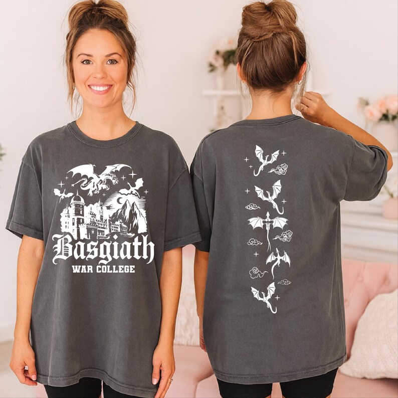 A woman wearing a grey t-shirt with a graphic design featuring a castle and dragons, smiling at the camera.