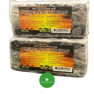 May include: Two wrapped bars of 100% Natural African Black Soap. The soap is dark in colour and packaged in clear plastic. The label includes the product name, ingredients, and net weight of 454g. The soap is made in Ghana and manufactured in the USA.